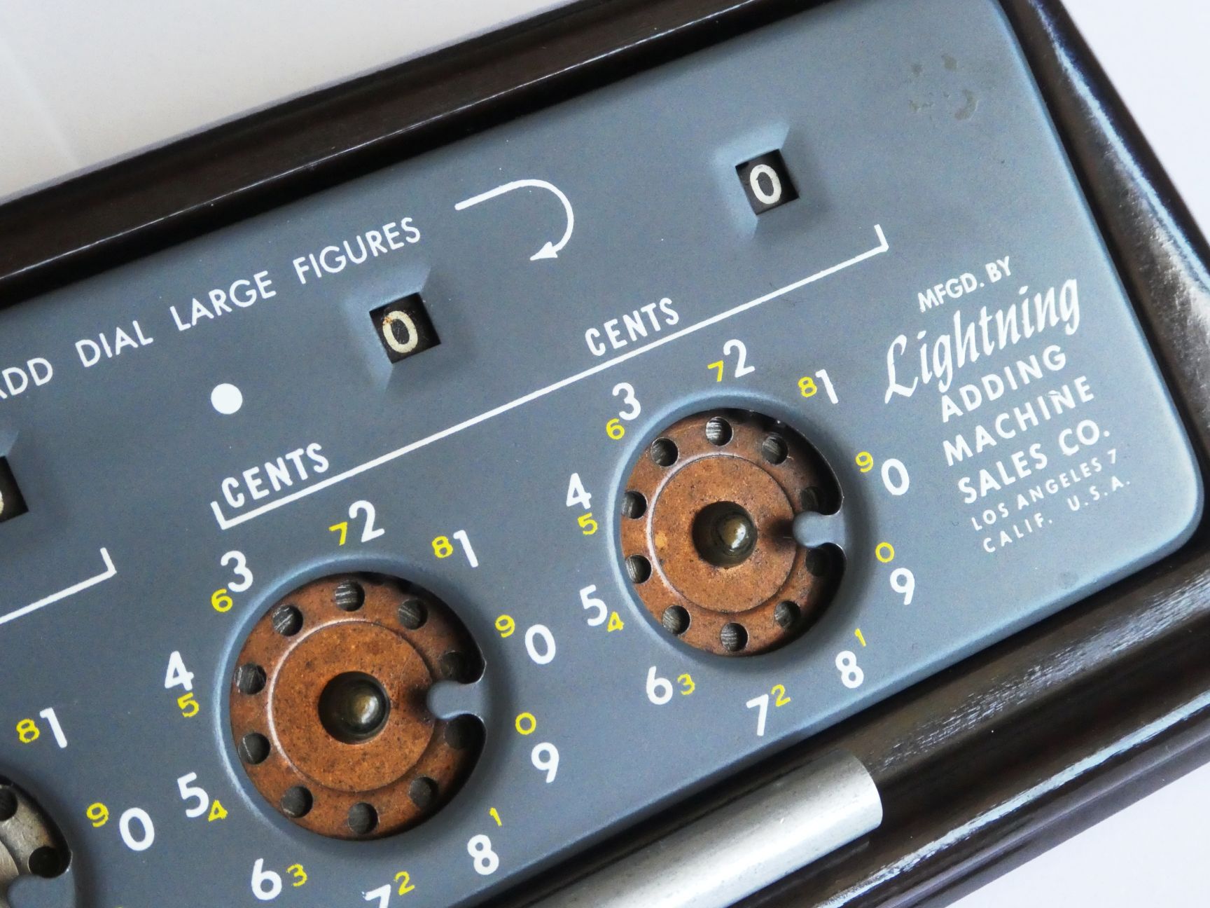 Figure 2 — The cents dials of a grey subtracting Lightning: the large white adding figures, the small yellow subtracting figures beside them, the stop between 9 and 0, and the maker's name, "Mfgd. by Lightnin…
