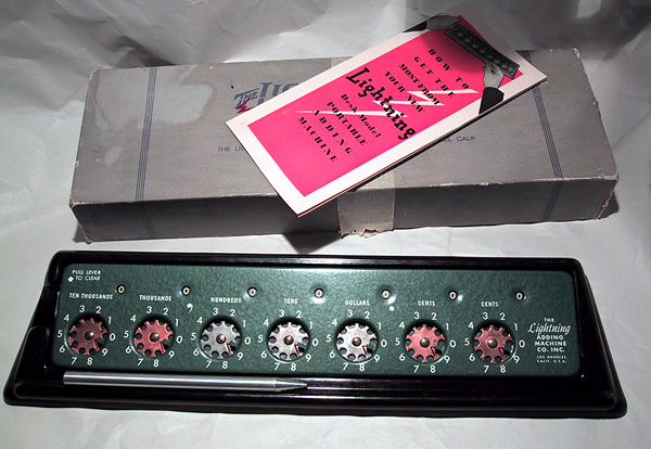 Figure 11 — A green clearing-lever machine on a black stand, with its box and pink instruction leaflet.