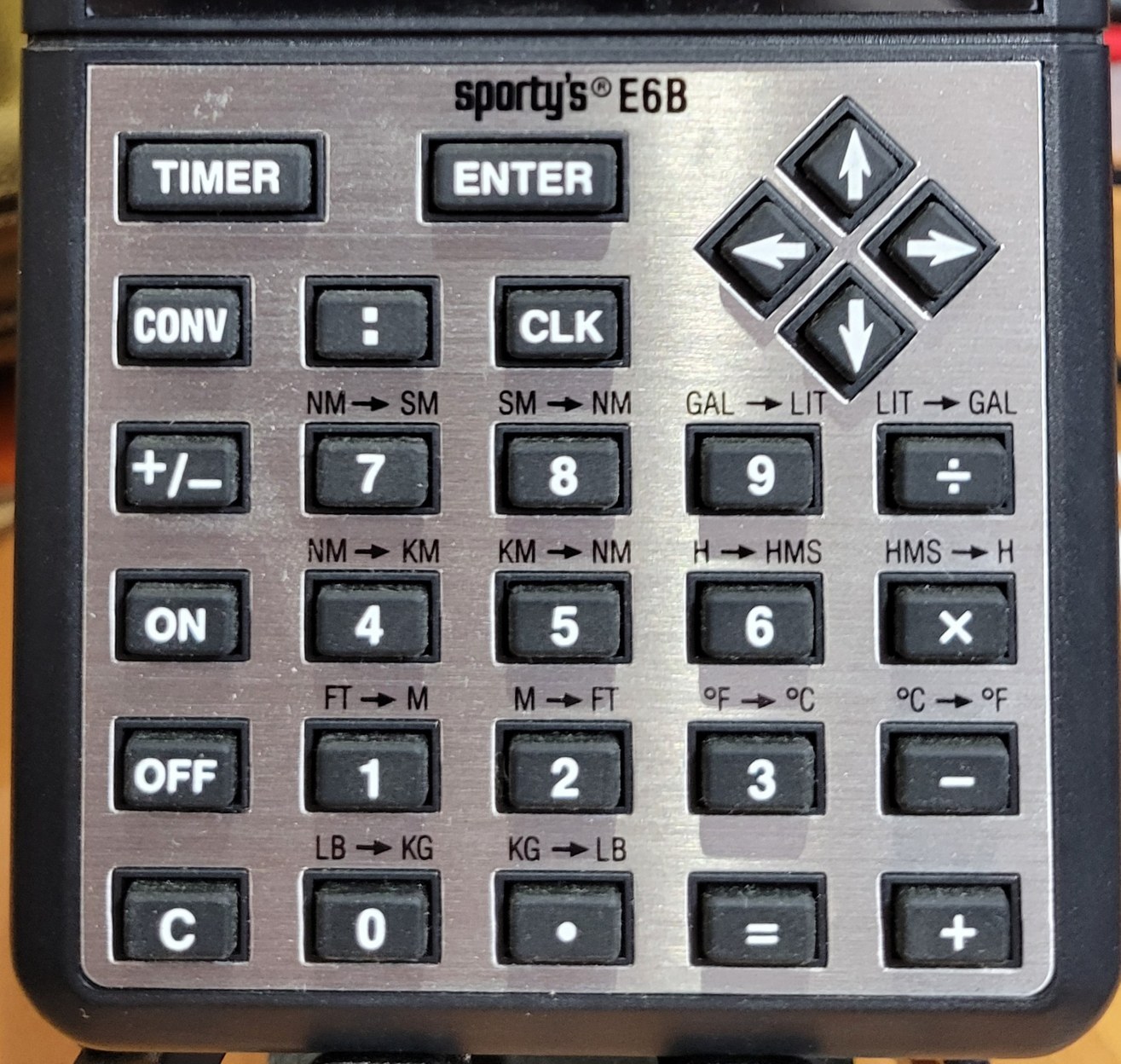 Figure 3 — My E6B's keypad: TIMER and ENTER, the arrow pad that moves the menu cursor, CONV and its fourteen conversions printed above the keys, the : key for hours-minutes-seconds, and CLK for the three clocks.