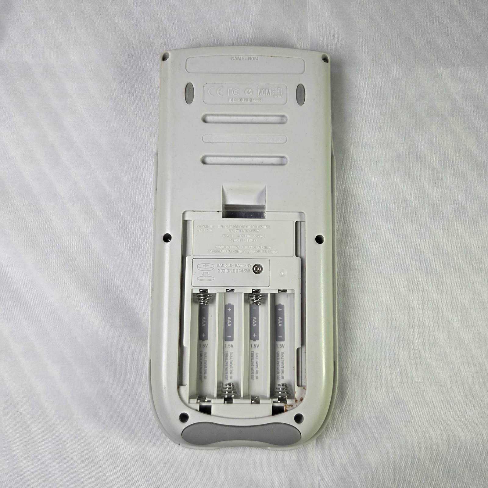 Figure 2 — The battery compartment of a TI-84 Plus Silver Edition: four AAA cells, with the backup button cell under its own screwed cover.