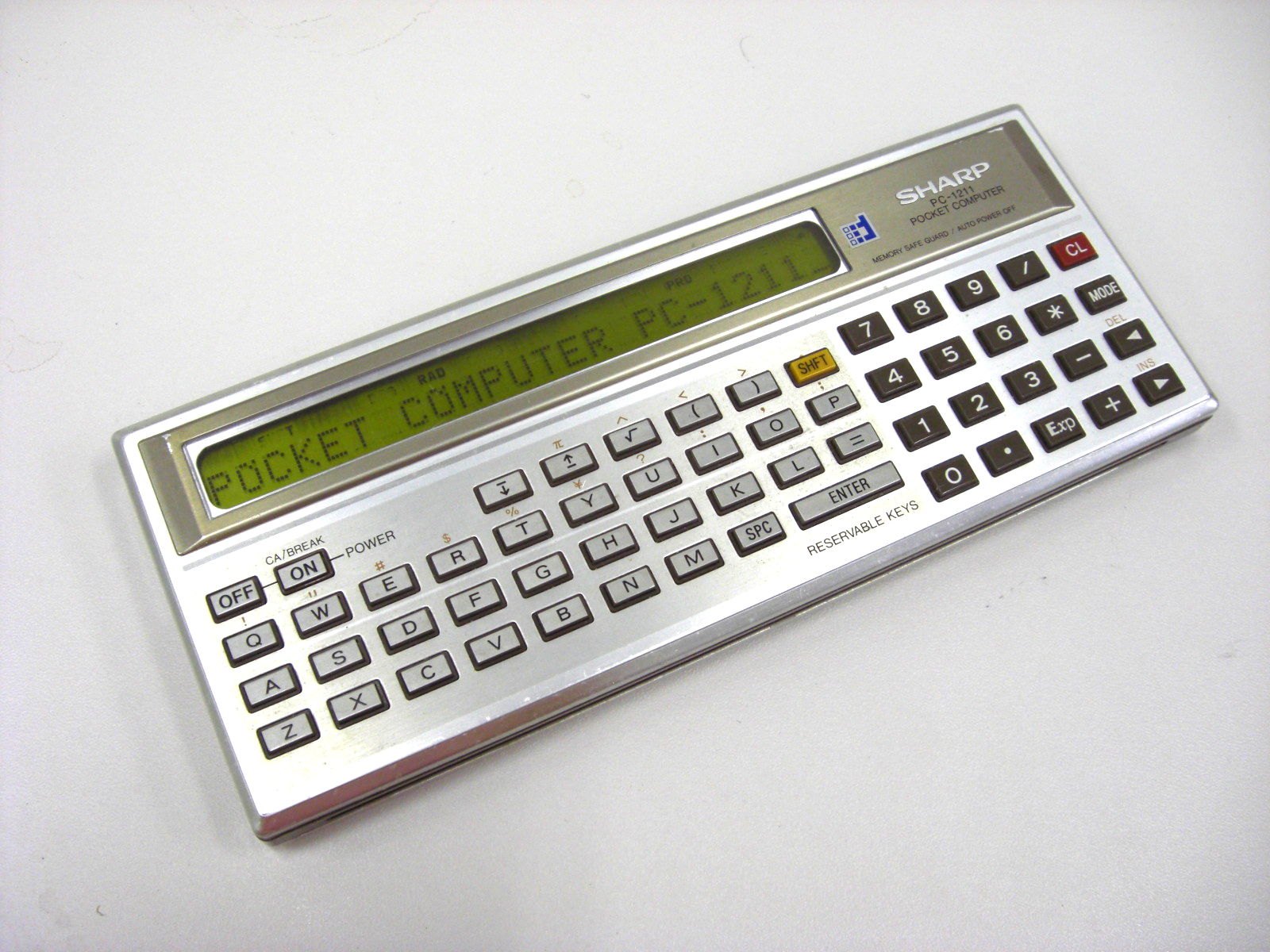 Figure 5 — A Sharp PC-1211 with a message on its display. Sharp's case is brown; Radio Shack's is black.