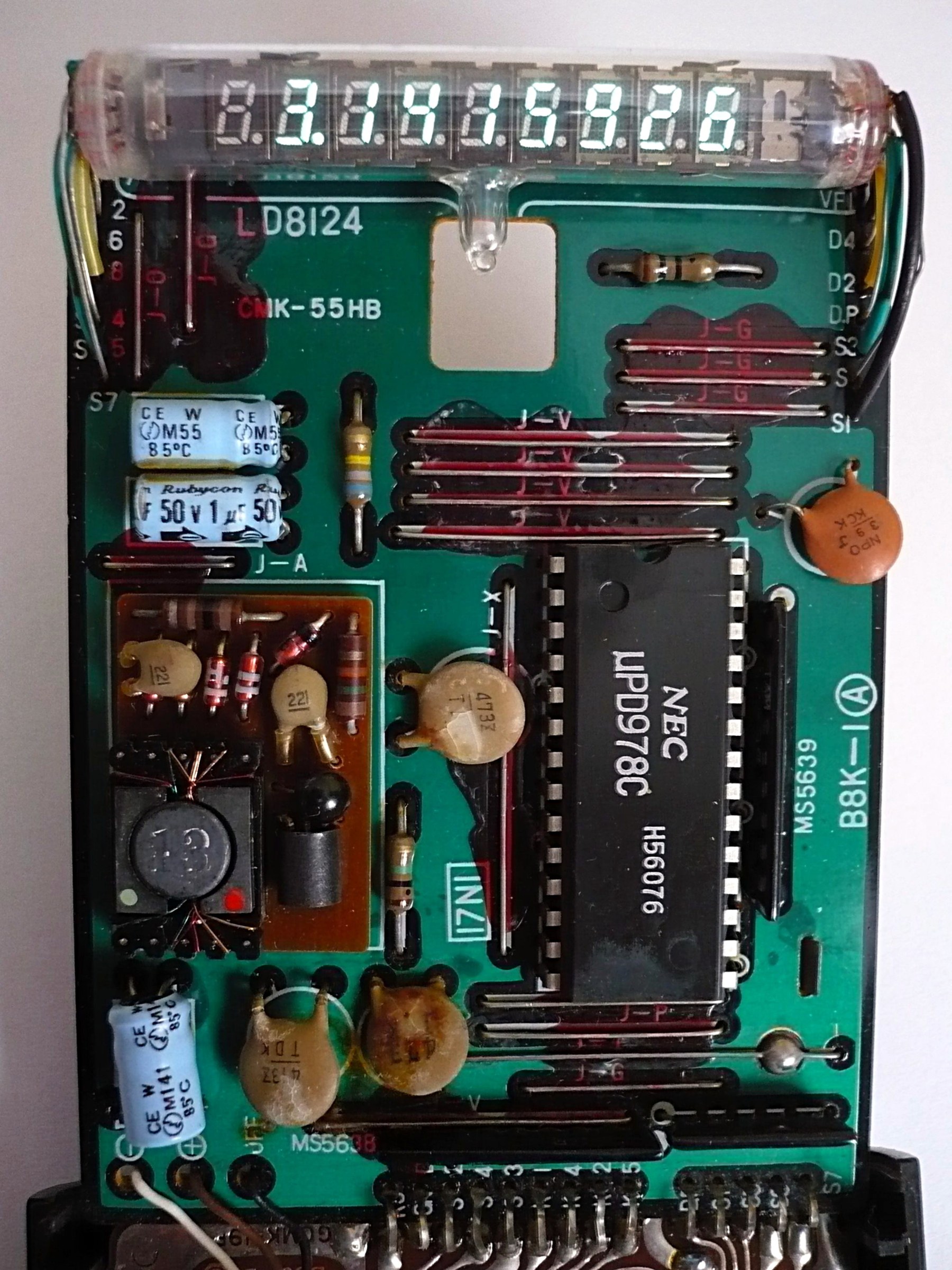 Figure 14 — Inside a Casio fx-20 of about 1976: the NEC LD8124 multi-digit tube across the top, the calculator chip, and the parts of the small converter that makes the tube's voltages from the cells.